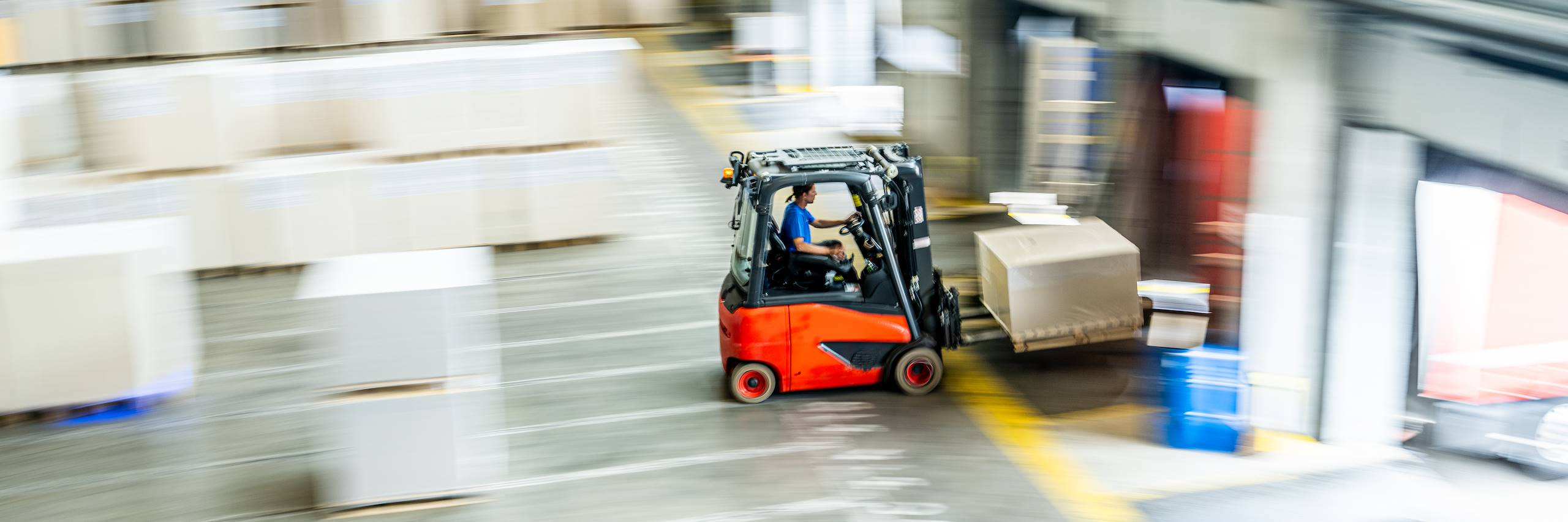 Gabelstapler transportiert eine Palette durch eine Lagerhalle in Richtung Verladetor